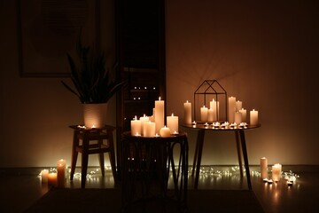 Many burning paraffin candles in dark room