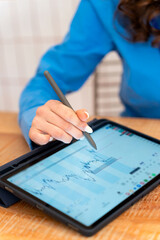 Businesswoman analyzing financial charts on digital tablet with stylus