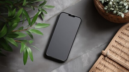 Smartphone with blank screen on stone surface surrounded by plants and rattan decor.
