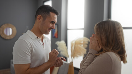 Obraz premium Man proposing to woman in elegant living room filled with love, excitement, and emotion, creating a memorable couple moment indoors in an apartment setting.