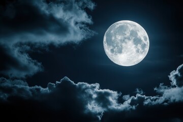 Full moon shines brightly in a dark blue night sky with clouds.