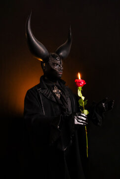 Mysterious Figure Holding Rose with Candlelight in Dark Ambiance