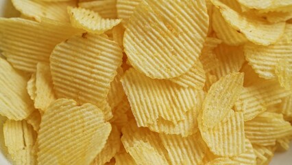 Close-up shot of fresh, crispy potato chips arranged in a pile showcasing texture and golden brown color.