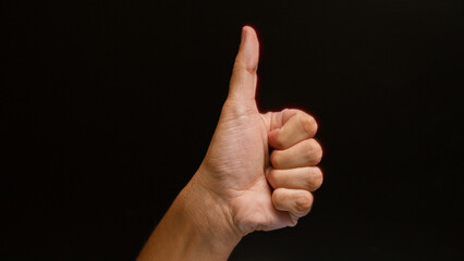 Man showing a thumbs up with his hand against a black background