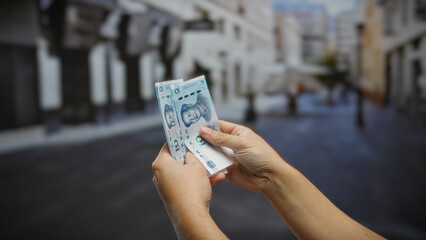 Man holding chinese yuan banknotes on an urban street, showcasing currency against a city backdrop,...