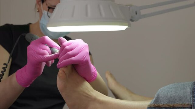 Pedicure specialist polishing sole dead skin callus removing using professional grinder grinder tool. Beauty salon self-care routine healthy nails treatment and small business daily workflow 4K video