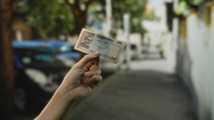 Man holding bangladeshi taka banknote on a city street, capturing the vibrant outdoor setting in an...