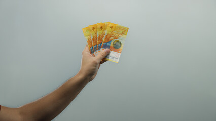 Man displaying swiss franc banknotes in hand over isolated white background, emphasizing clarity...