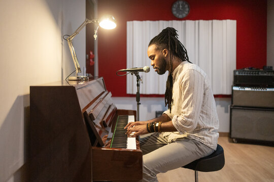 Musician playing piano and singing in professional studio
