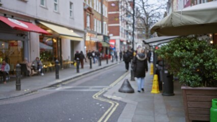 People walking on a blurry london street with autumn leaves, creating a cozy urban atmosphere during winter in the uk with cafes and shops lining the path.