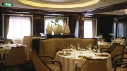 Luxury restaurant interior with elegant table settings and blurred bokeh lighting creating a warm ambiance indoors for fine dining experiences.