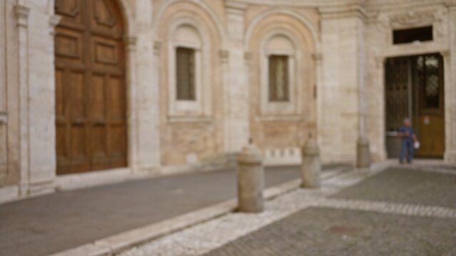 University campus with blurred man walking outdoors near old stone building entrance featuring cobblestone path and arched windows in a defocused background setting