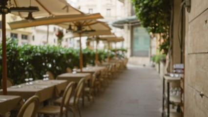 Blurred bokeh view of an outdoor cafe with empty tables and chairs on a picturesque street in rome, italy, creating a serene and inviting ambiance.