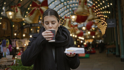 Woman enjoying hot drink in festive covent garden surrounded by christmas lights, capturing a joyful moment on a london street during winter holidays.