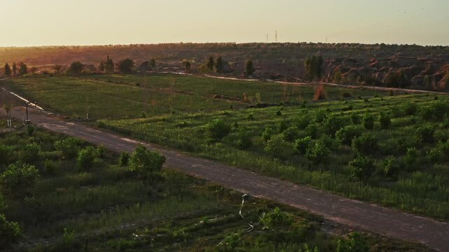 Drone view of a road in lush rural fields at sunset in Chakwal, Pakistan