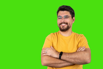 Smiling man with crossed arms in front of green chroma key background, confident and relaxed, isolated studio shot, looking at camera with positive expression.