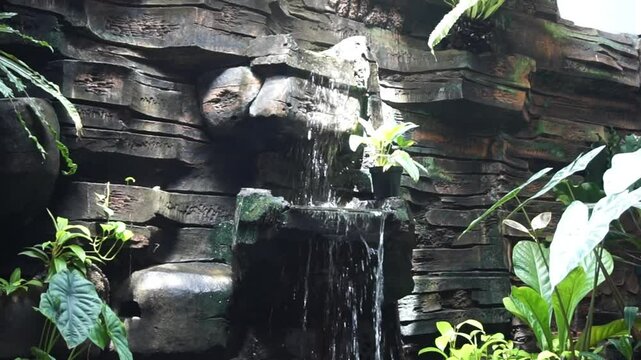 artificial mini waterfall and artificial rock wall and flowing water in artificial fish pond, and some beautiful ornamental plants