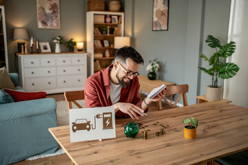 Man calculating savings for electric car charging at home