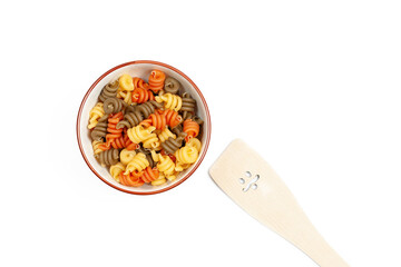Tricolor pasta in bowl with wooden spatula on white background
