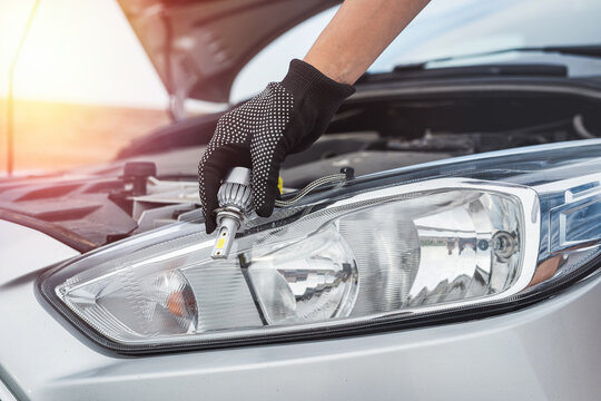 Fototapeta  A man is fixing a car with change light bulb