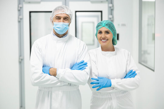 Two healthcare workers stand confidently in a sterile lab setting, showcasing teamwork and professionalism in medicine.