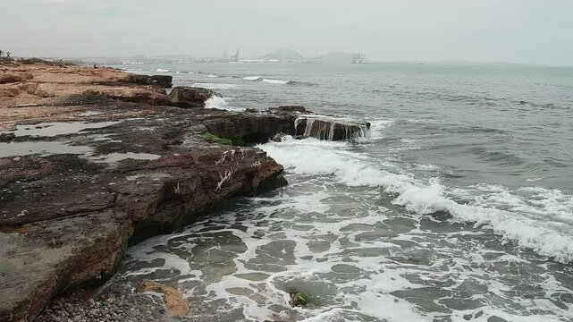 Paisaje mediterr&aacute;neo en d&iacute;a de lluvia ligera con olas rompiendo en las rocas costeras, Alicante, Espa&ntilde;a