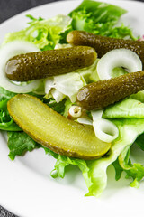 Salad cucumber pickle gherkins pickled mixed green leaf lettuce appetizer vegetable dish organic fresh tasty gourmet food background on the table