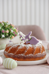 Traditional easter cakes with icing decorated with gingerbread cookies in shape of rabbits on white wooden table