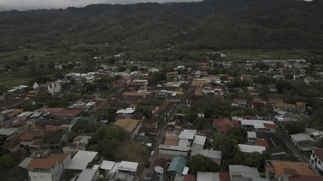 Drone orbits to the left from north side of city to the east in wide view of Copan, Honduras on cloudy day