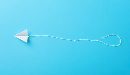 Paper Airplane Tethered on a Blue Background