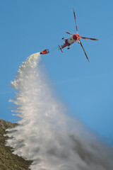 Firefighting helicopter dropping water from Bambi bucket