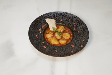 A plate of food with a garnish on top. The plate is black and the garnish is white