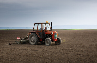 Farmer with tractor seeding in sunset