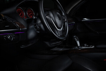 Close-up view of a car's dashboard at night with illuminated controls and a black background.
