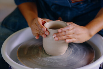 Close-up of a Latina woman’s hands shaping a ceramic piece in her workshop. The image captures effort, focus, and handcrafted detail.
