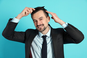 Handsome man stylish his hair with comb on light blue background