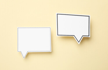 Blank speech bubbles on beige background, top view. Space for text