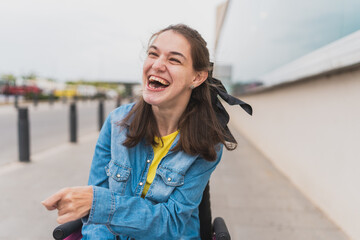 Portrait of young woman with cerebral palsy laughing joyfully outdoors - She radiates happiness and...