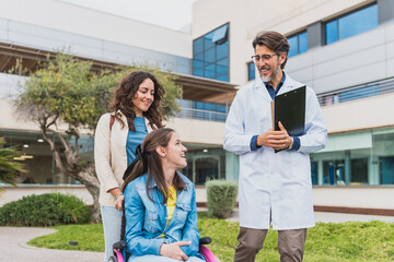 Doctor talks with young woman with cerebral palsy and her personal assistant - Friendly exchange...