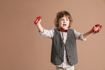 Cute little boy playing toy tambourines on brown background