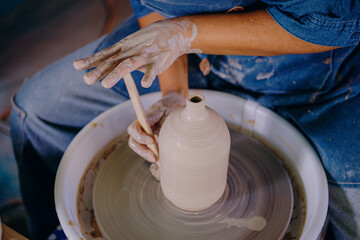 Close-up of a Latina woman’s hands shaping a ceramic piece in her workshop. The image captures effort, focus, and handcrafted detail.
