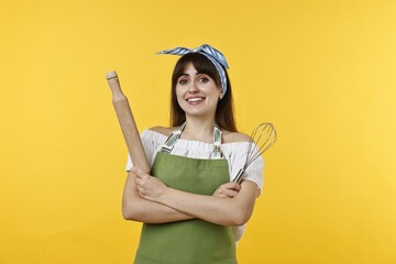 Woman with rolling pin and whisk on yellow background