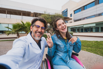 Naklejka premium Young woman with cerebral palsy and doctor taking cheerful selfie - Smiling young woman with cerebral palsy poses with her doctor for a joyful selfie after medical session. Concept of cerebral palsy.