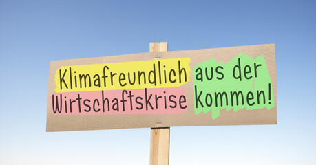 Kartonschild mit der Devise; klimafreundlich aus der Wirtschaftskrise kommen!