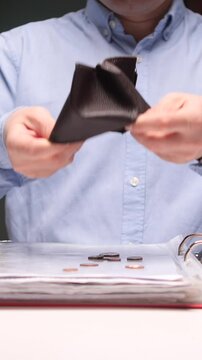 vertical video Businessman emptying wallet with last coins falling on desk at office