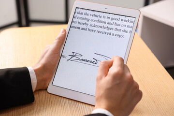Electronic signature. Man using tablet at wooden table, closeup