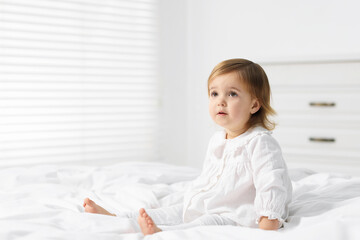 Cute little baby girl on bed at home. Space for text