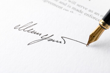 Fountain pen leaving signature on paper, closeup