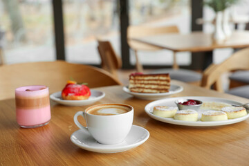 Delicious cottage cheese pancakes, desserts and aromatic coffee served on wooden table in cafe