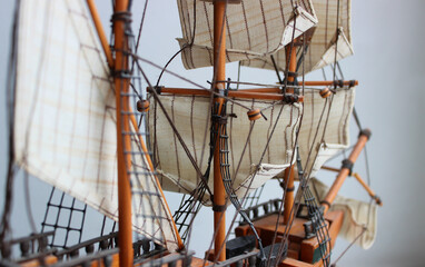 View along the deck of a wooden model of a medieval sailing ship to the bowsprit in defocus. Close up of the masts and yards on which the ropes and sails are strung. Hobby of assembling scale models